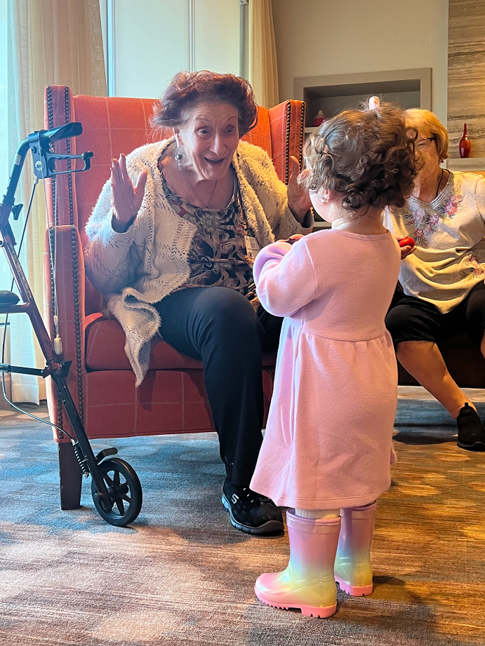 A senior participant reacting with delight to a toddler during a Bach & Boogie session